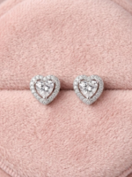 Heart shaped silver halo stud earrings with sparkling crystals resting on a soft pink velvet background⁠